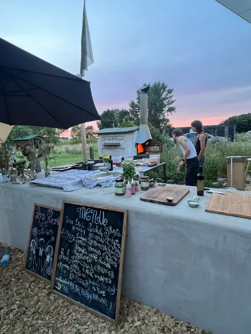 Udendørs bar med tavler og skilte i aftenlys.
